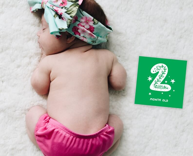 Sleeping baby next to a sign customized with 2 months old