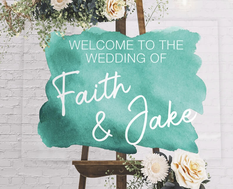 Customized welcome sign on an easel for wedding of Faith & Jake with floral arrangements above and below