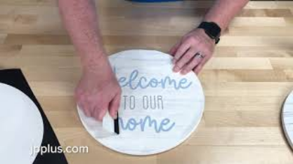 A wood round being customized with Welcome to our home