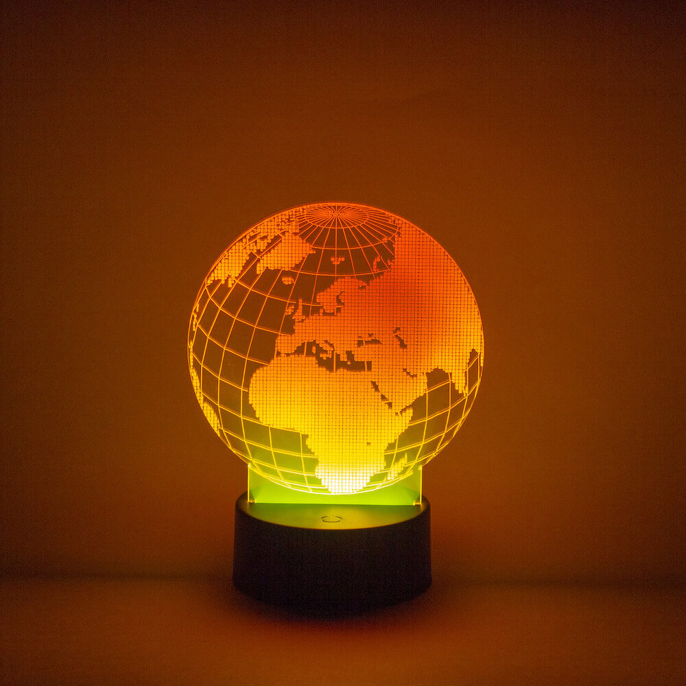 acrylic design of a globe atop a round light base that makes the design shine in a yellow-orange